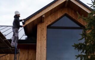 2149343675-min Two workers installing roofing on a wooden house in a residential area.