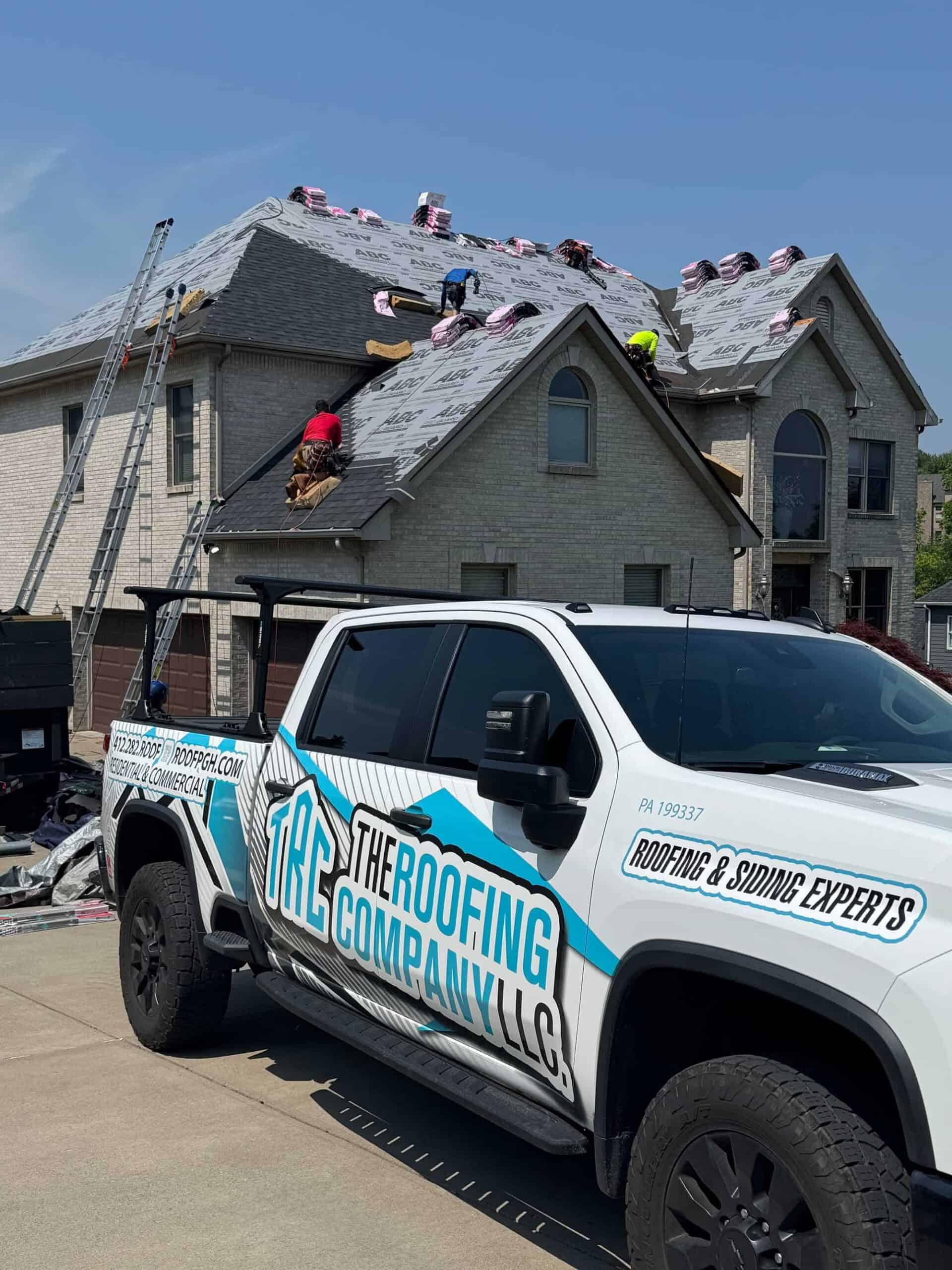 IMG_3344_1770663926562-B6r_niaM (1) Roofing workers install new shingles on a large residential home in daylight.