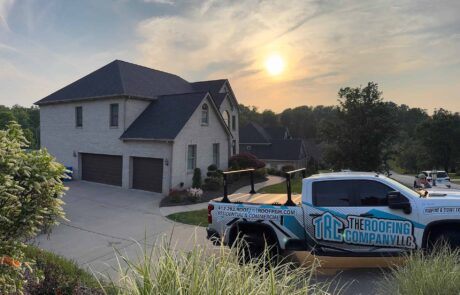 IMG_3368 The Roofing Company truck parked in front of a large residential home at sunset.
