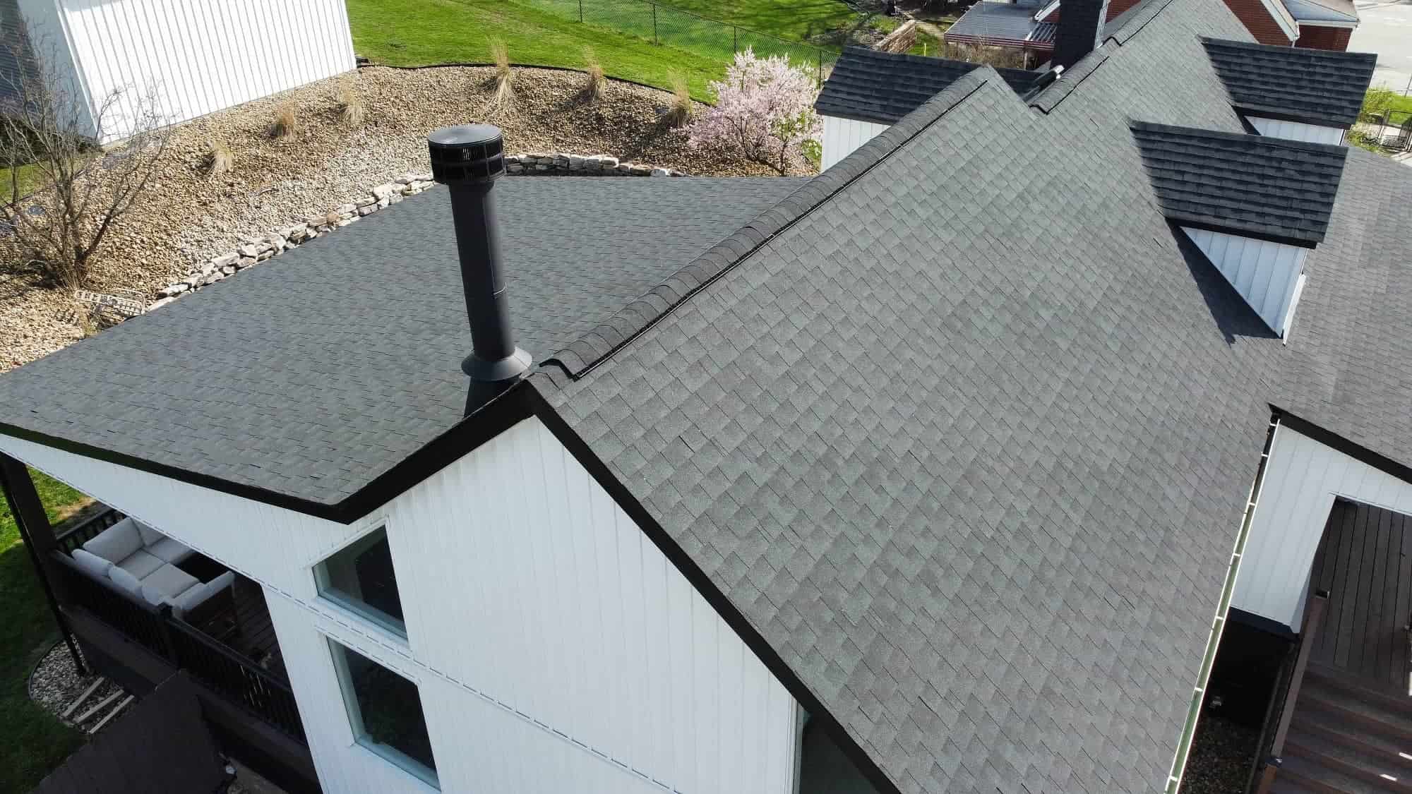dji_fly_20250414_164236_553_1745076689442_photo_optimized_1769534459250-vPU94CYC (1) (1) View of a residential roof with gray shingles and a black chimney pipe.