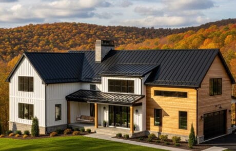 metal_roof_farmhouse-DhiCVSy1 Modern two-story house with black metal roof and wooden siding in a scenic fall landscape.