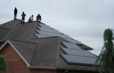 Workers installing solar panels on a residential shingle roof in Pittsburgh.